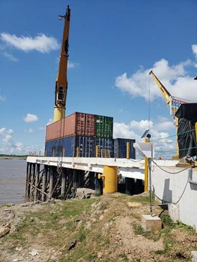 Pier on the Ucayali river in Pucallpa with containers and a crane, and the station on a pole