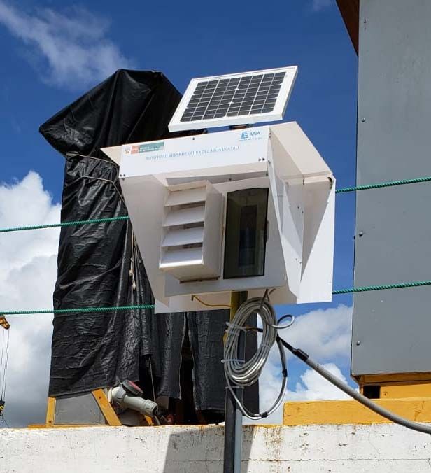 Hydrometric station of AAA Ucayali in Pucallpa, Peru: enclosure with louvres and a small solar panel on top, on a pole by the river