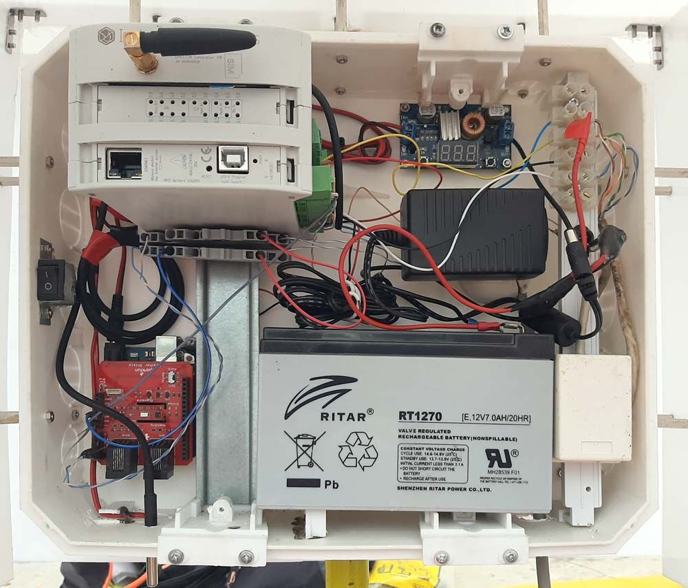 Inside the station cabinet: Industrial Shields PLC with an antenna, a 12 V 7 Ah battery, a DC-DC converter and wiring